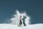 Zwei Snowboarder erzeugen einen Schnee-Spritzer auf der Piste
