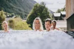 vier Personen in einem Whirlpool mit natürlicher Umgebung im Hintergrund