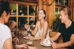 Gruppe von Freunden, die Dessert an einem Holztisch in einer gemütlichen Umgebung genießen