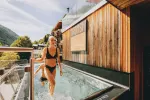 Frau im Bikini, die aus einem Pool tritt, mit Holzfassade im Hintergrund