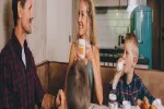 Familie sitzt am Tisch und genießt Getränke und Essen.