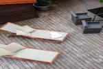 Zwei Liegen mit Kissen auf einem Holzdeck, daneben Tische.