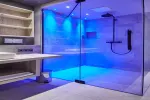 Modernes Badezimmer mit blauer Beleuchtung und Glasdusche