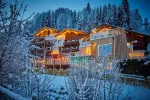Gemütliche Holzhäuser in einer verschneiten Landschaft beleuchtet.