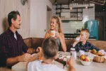 Familie versammelt sich um einen Tisch mit Essen und Getränken in einer gemütlichen Küche