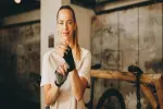 Frau lächelt im Fitnessstudio, trägt Trainingshandschuhe, bereit für das Training