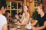 Menschen sitzen an einem Holztisch in einem gemütlichen Restaurant.
