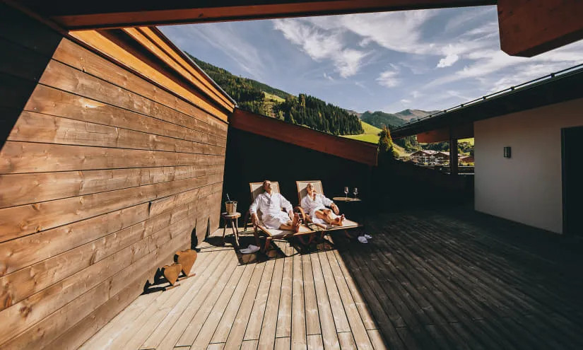 Zwei Personen in Bademänteln auf einer Terrasse im Thomsn Hinterglemm.