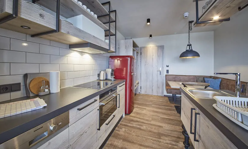 Moderne Küche mit Holzschränken, rotem Kühlschrank und Essbereich