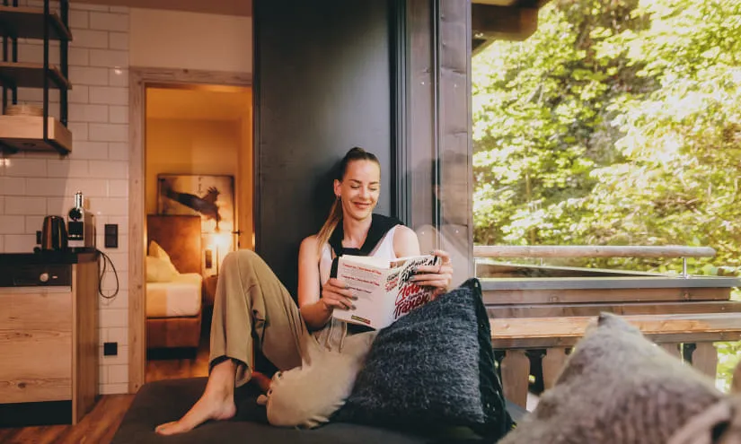 Frau sitzt auf einem Sofa und liest ein Magazin im Thomsn Hinterglemm Appartment