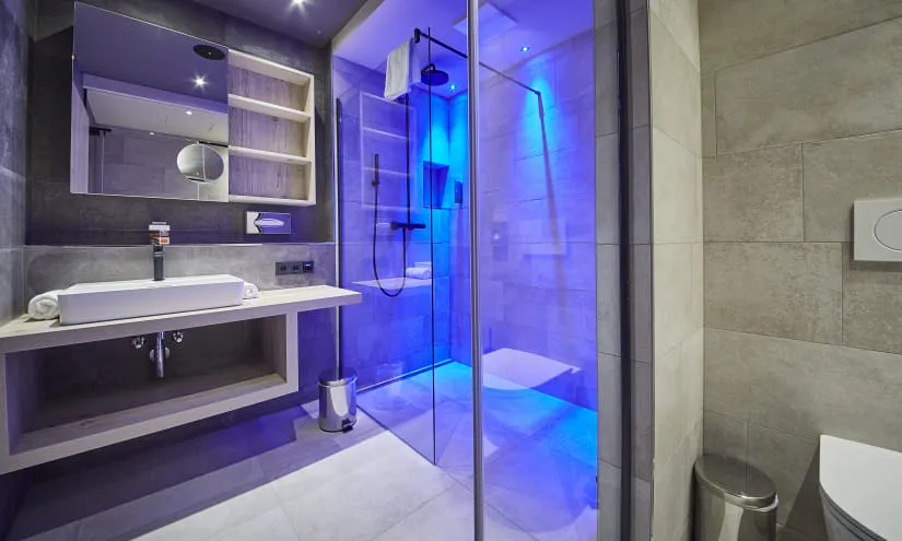 Moderne Badezimmeransicht mit Dusche und blauem Licht.