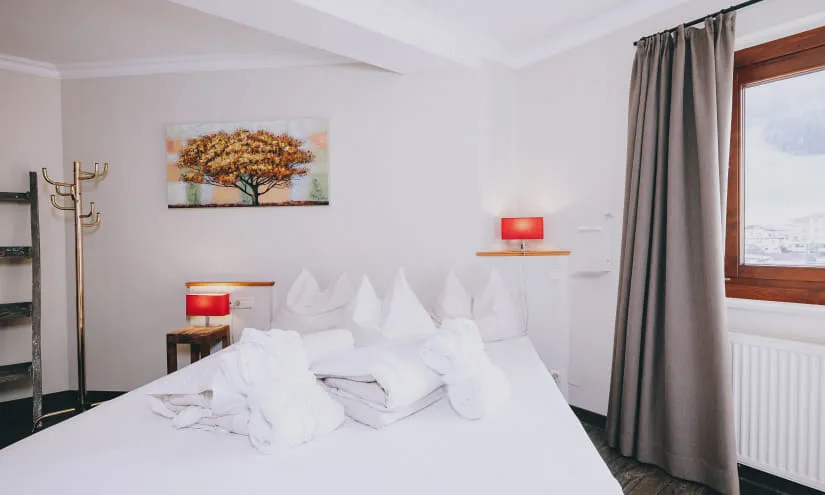 Helles Hotelzimmer mit Baumgemälde, Betten und Getränkeständer.