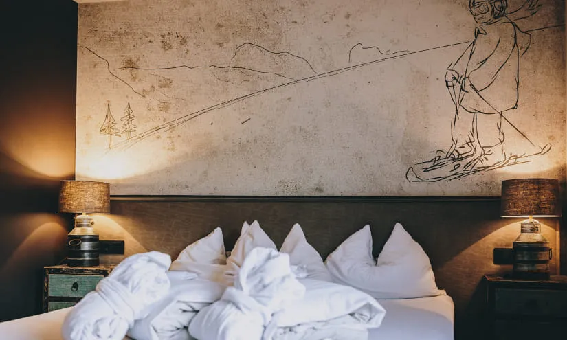 Hotelzimmer mit einem Bett und einer Wandmalerei eines Snowboardfahrers.