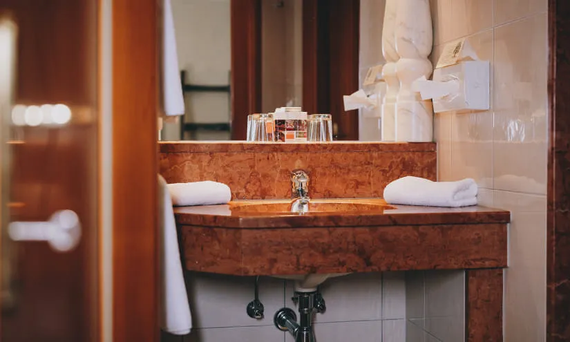 Elegantes Badezimmerwaschbecken mit Wasserhahn, Handtüchern und Toilettenartikeln