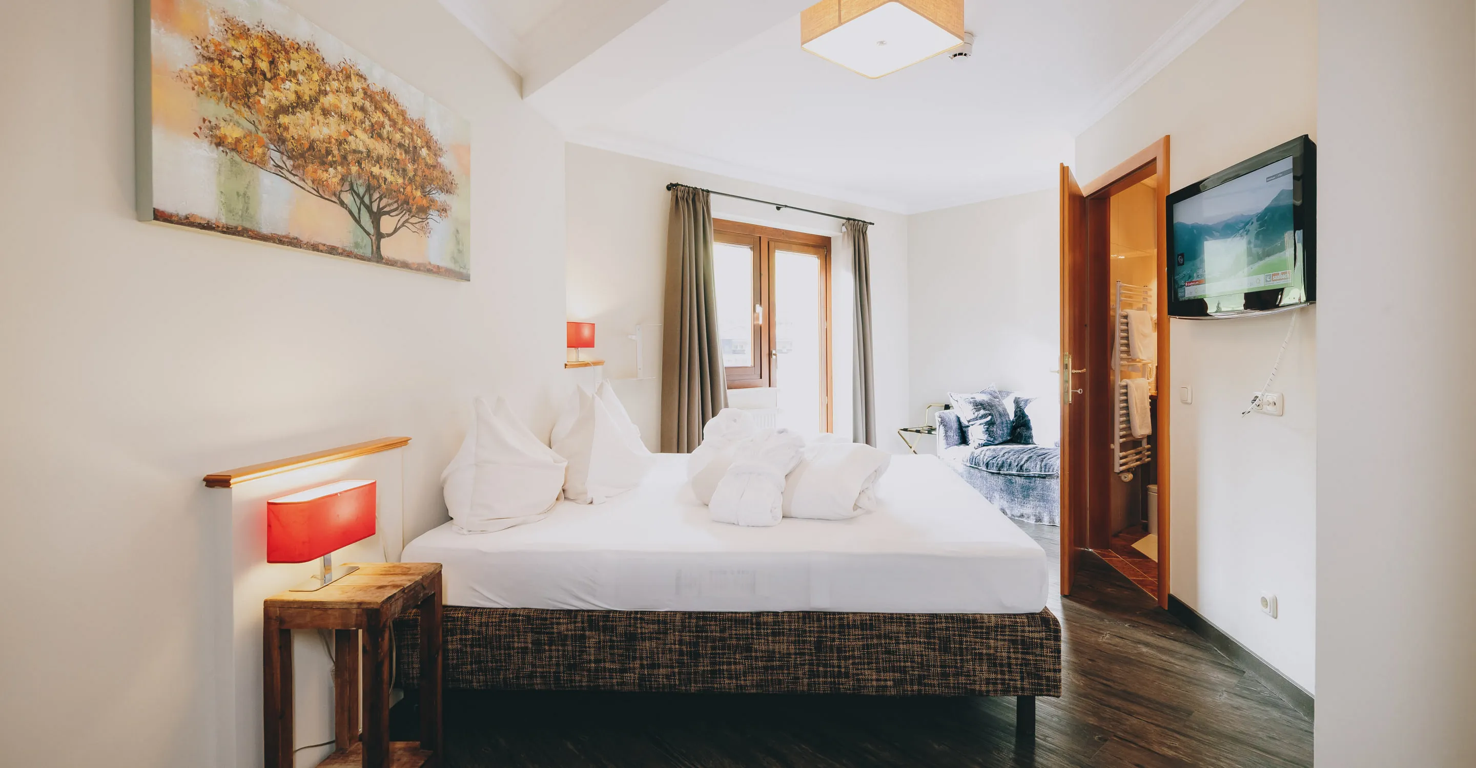 Schlafzimmer mit Bett, Kunstwerk, TV und Fenster.
