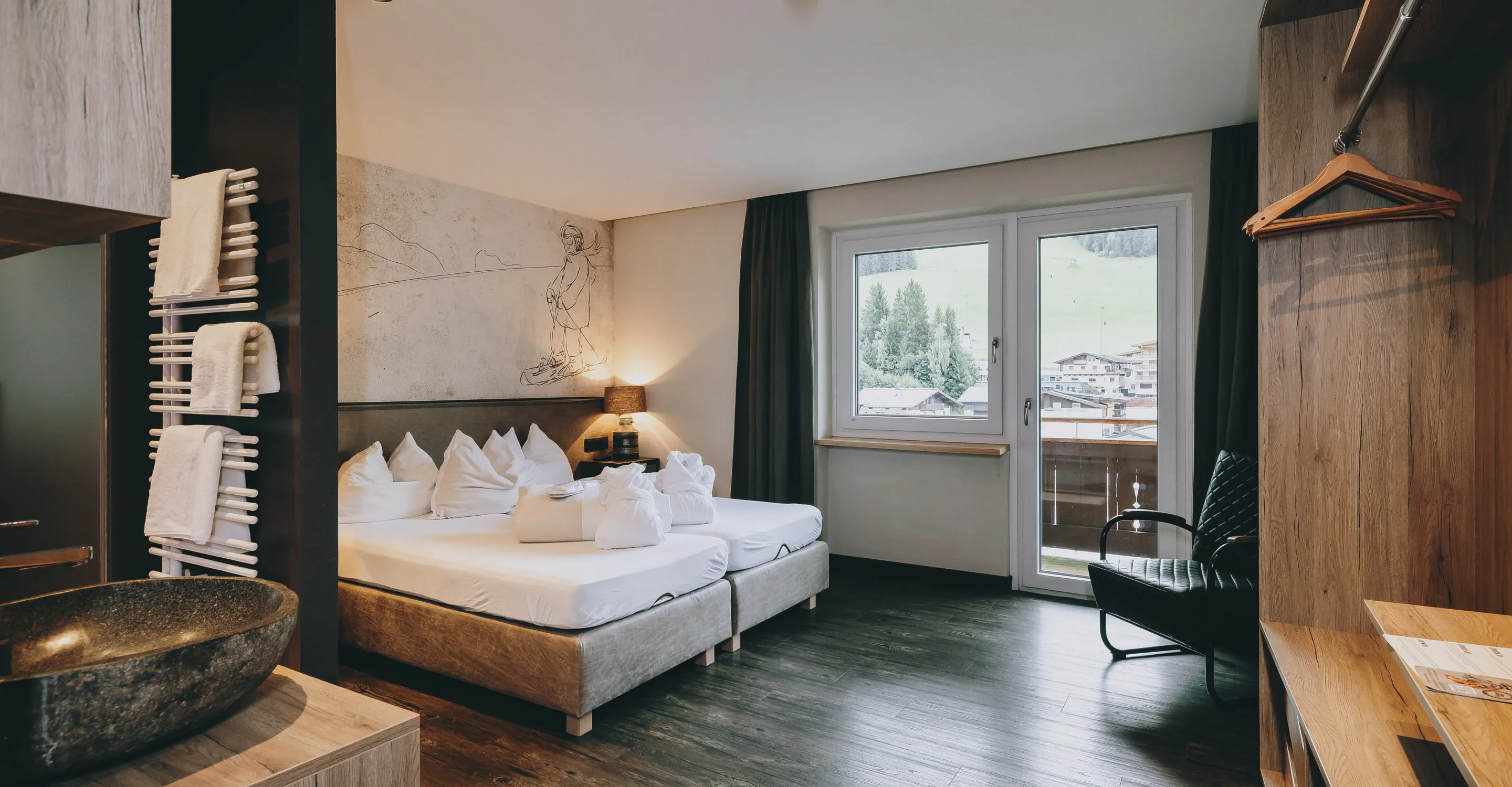 Helles Zimmer mit Betten, einem Balkon und Blick auf die Landschaft.