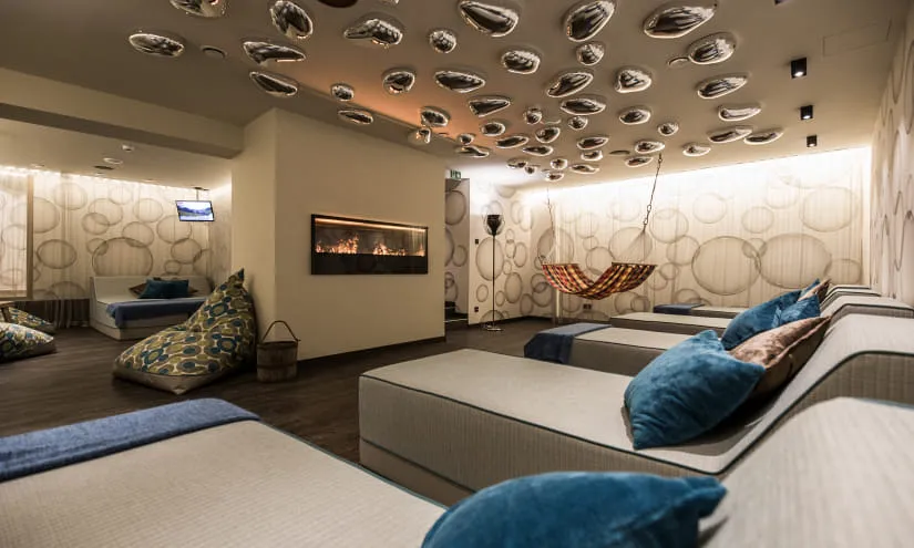 Moderne Wellness-Lounge mit Liegen, einem Kamin und einer hängenden Hängematte.
