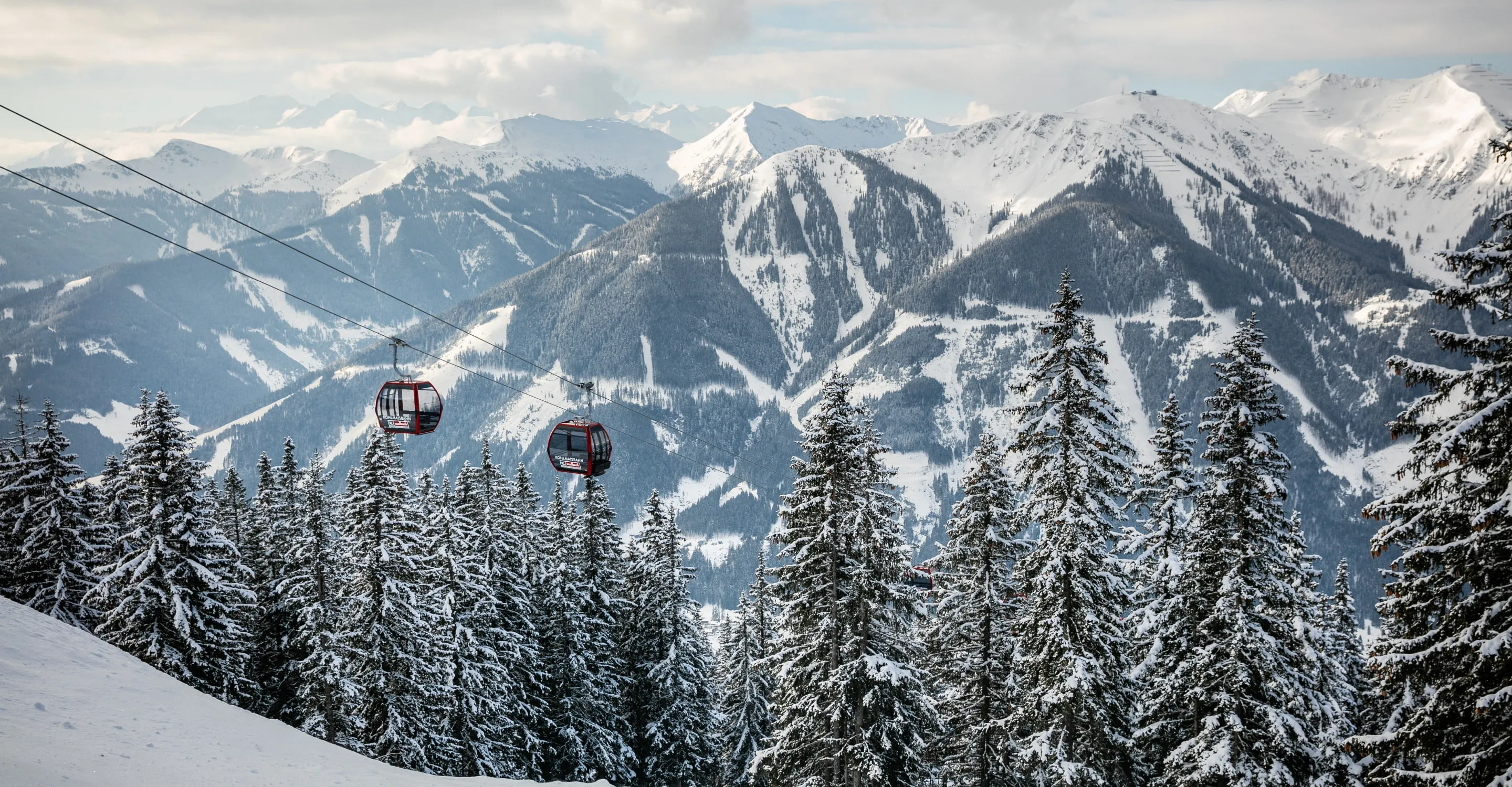 Skigondeln über verschneite Bäume und Berge in Saalbach-Hinterglemm-Leogang-Fieberbrunn