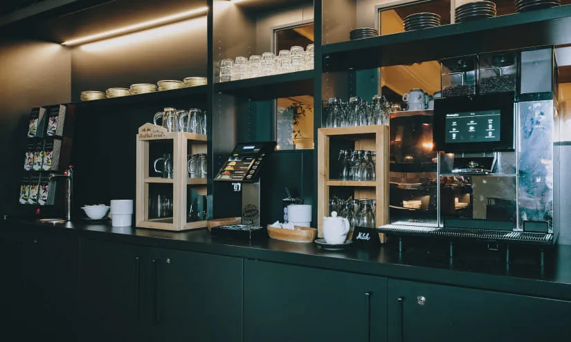 Moderne Frühstücksbar mit Gläsern, Geschirr und Kaffeemaschine.
