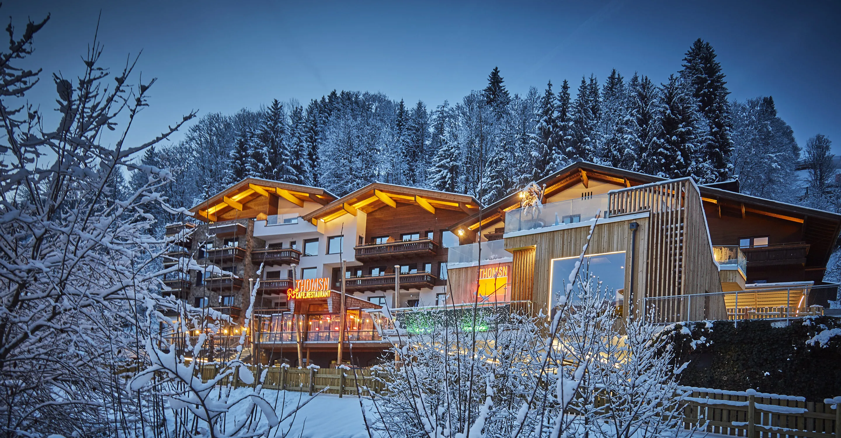Winteransicht eines modernen Chalets mit beleuchteter Architektur und schneeigem Landschaft