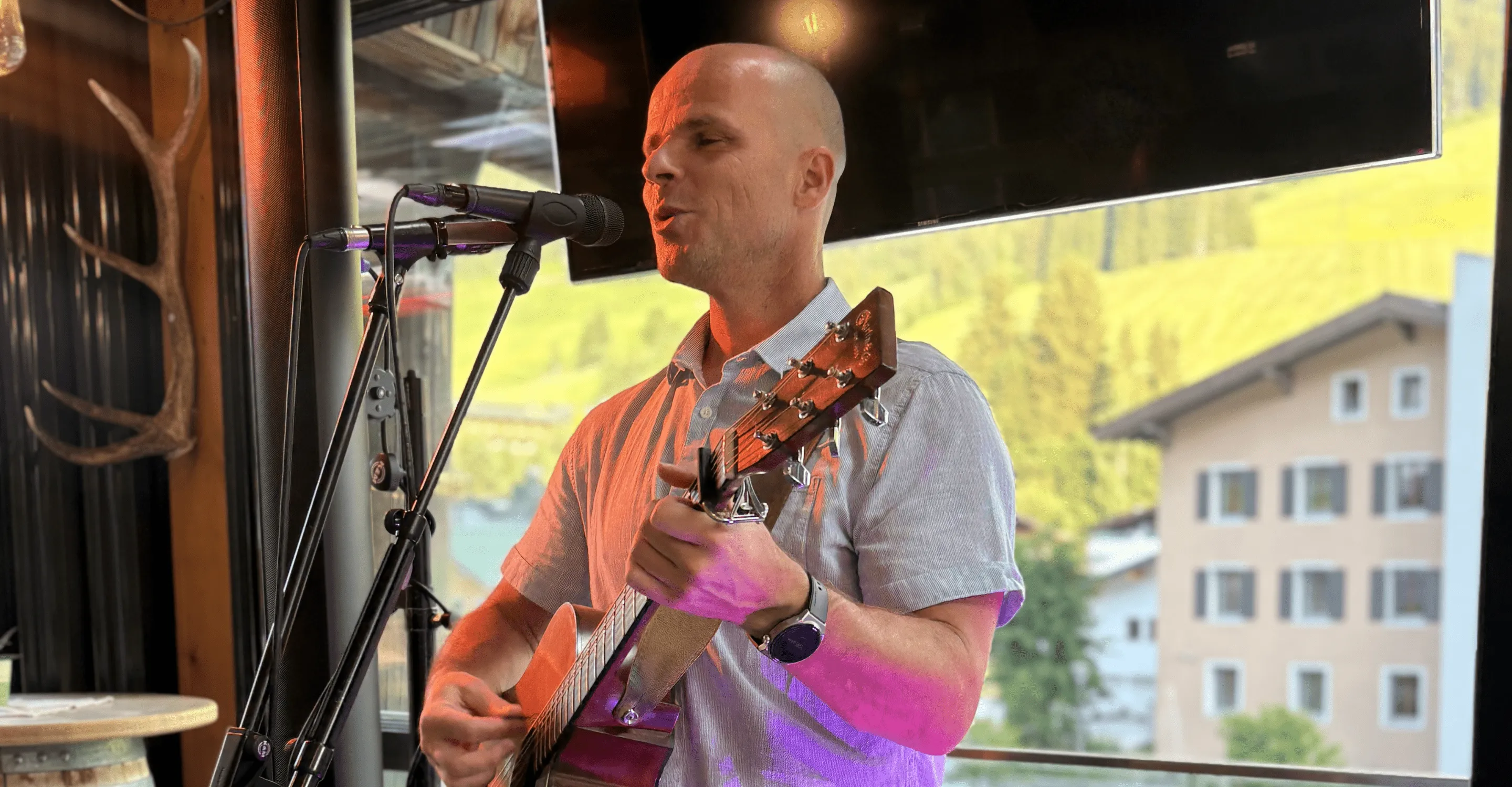 Mann spielt Gitarre bei einer Veranstaltung mit Bergblick