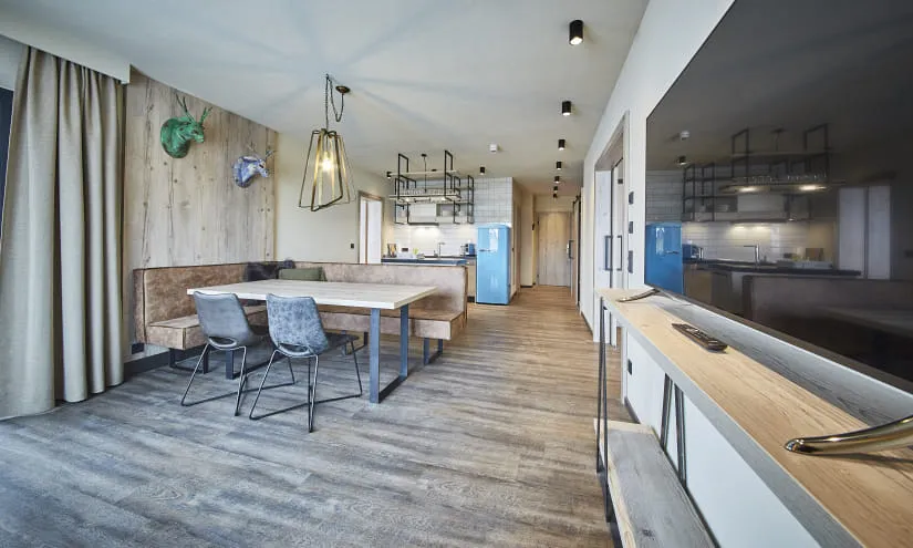 Moderne Küche und Essbereich mit Holzelementen und blauen Geräten.