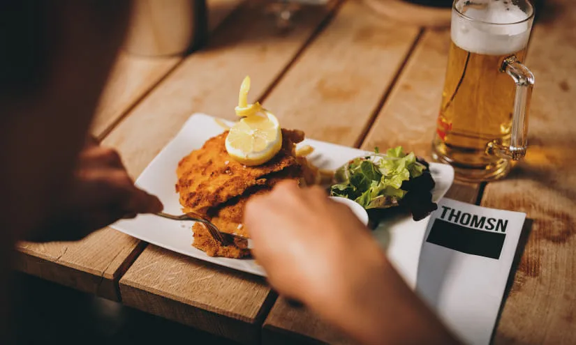 Ein Teller mit Schnitzel, Beilage, Zitrone und Bier, im Restaurant THOMSN.