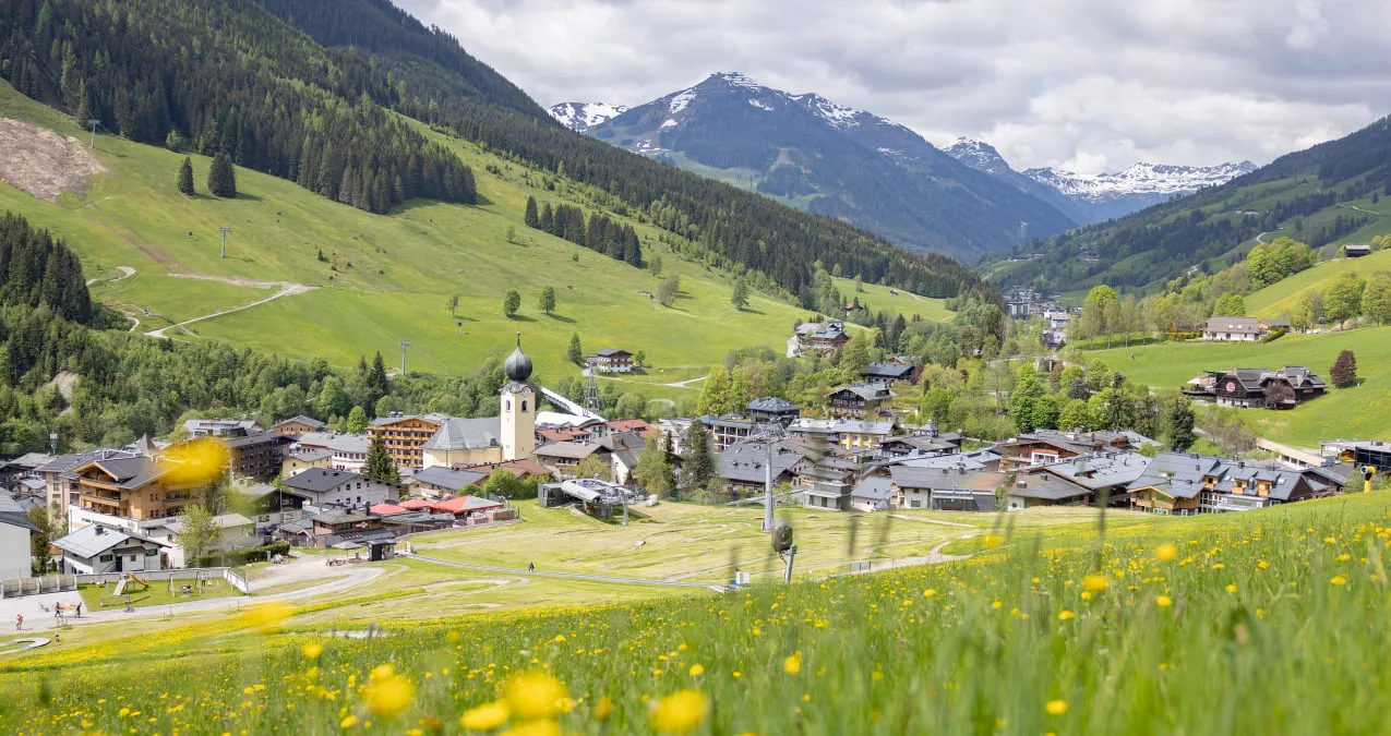 View of Saalbach village in the Alps with green meadows.