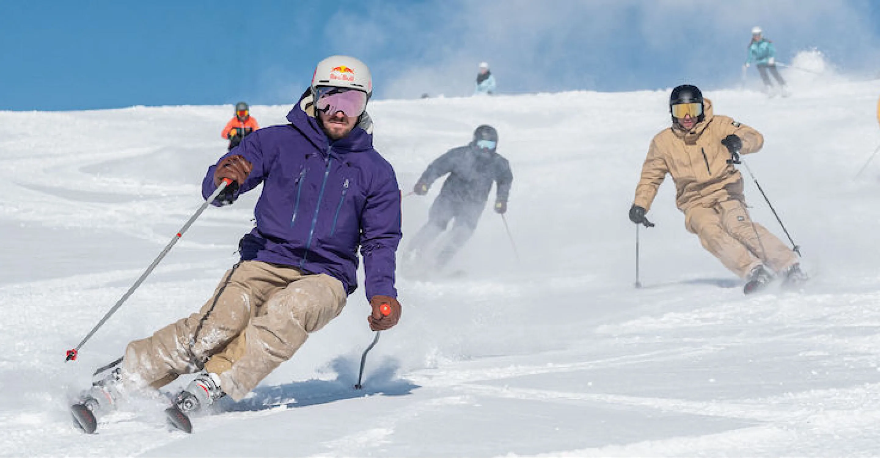 Skifahrer auf einer verschneiten Piste am White Pearl Mountain, blauer Himmel darüber.