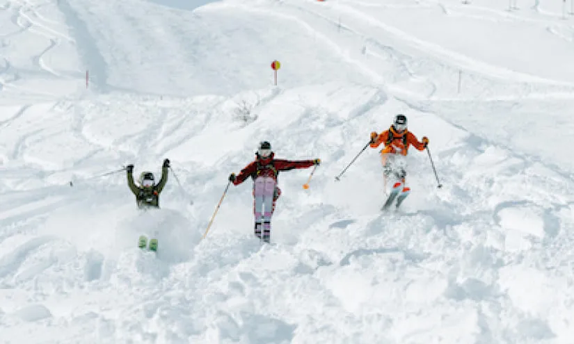 Drei Skifahrer im Tiefschnee auf einer Piste