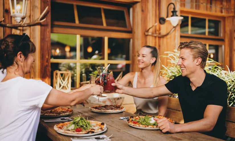 Freunde genießen Getränke und Essen in einem Restaurant in Hinterglemm.