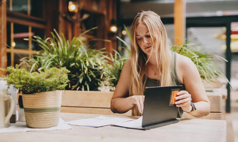 Junge Frau arbeitet an einem Laptop mit Pflanzen im Hintergrund