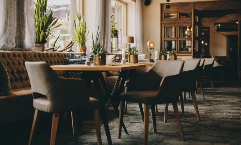 Gemütliches Restaurant mit Pflanzen und Holzstühlen.