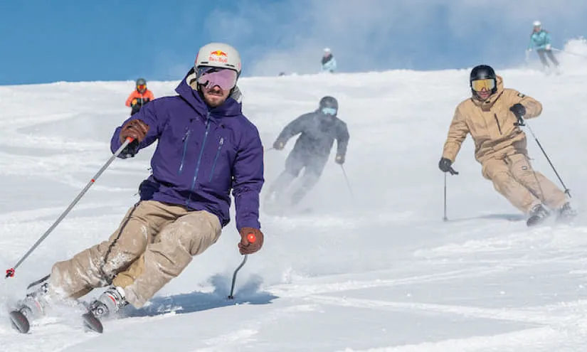 Skifahrer auf schneebedeckten Pisten unter klarem blauen Himmel