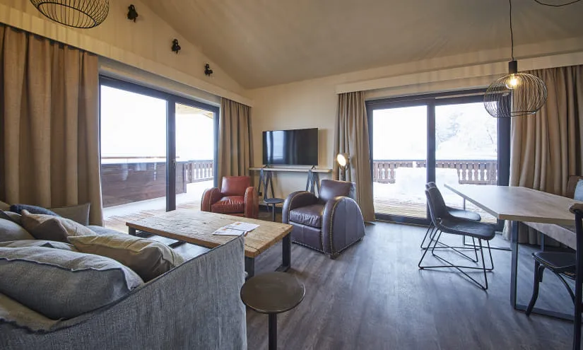 Modernes Wohnzimmer mit Sofas, Tisch, Stühlen und Fenster mit Aussicht.