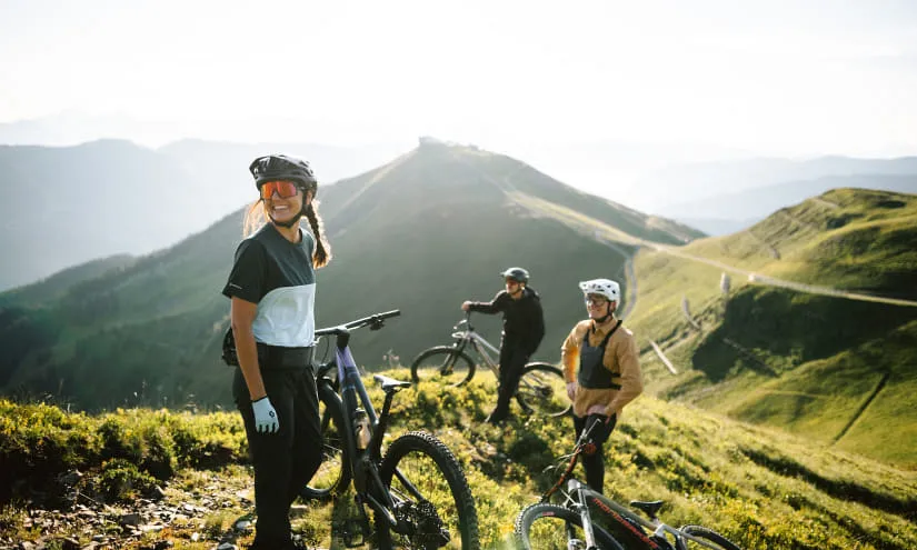 Drei Radfahrer in den Bergen mit Aussicht auf die Landschaft.