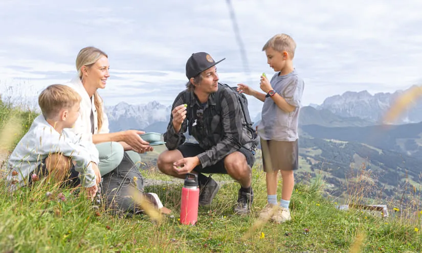 Familie beim Wandern, Pausensnack auf der Wiese