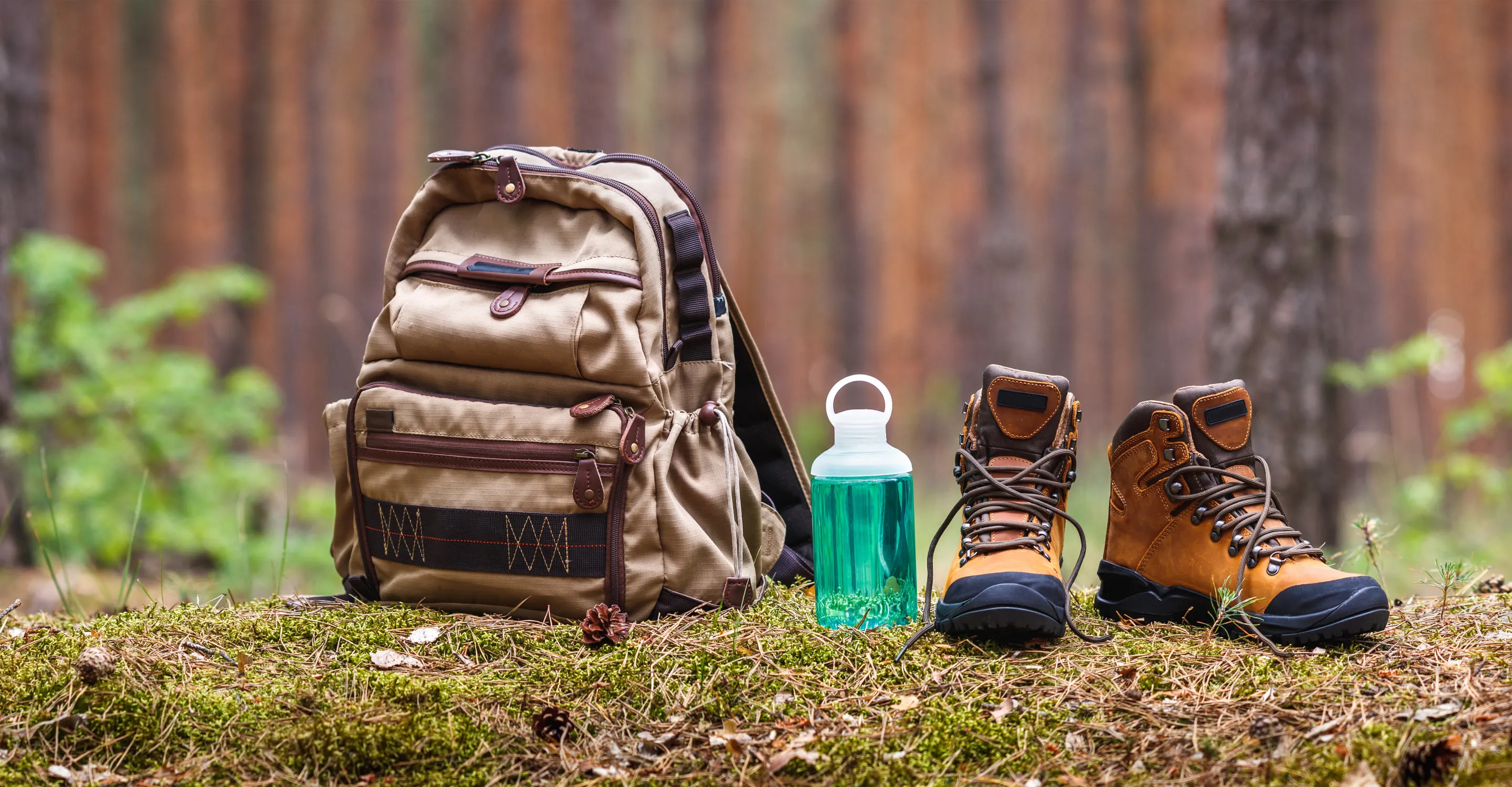 Rucksack, Wasserflasche und Wanderschuhe im Wald