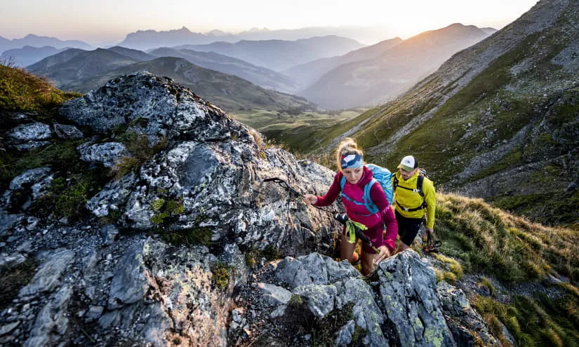 Wanderer erklimmen Felsen in Saalbach-Hinterglemm bei Sonnenuntergang