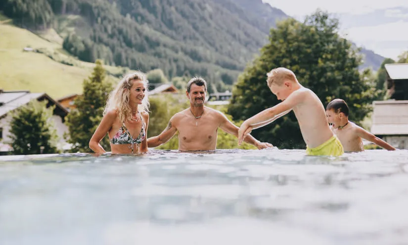 Familie, die in einem Pool mit Bergen im Hintergrund spielt