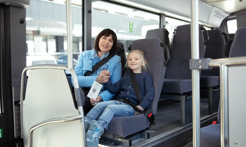 Frau und Kind im Bus mit Fahrkarte in der Hand