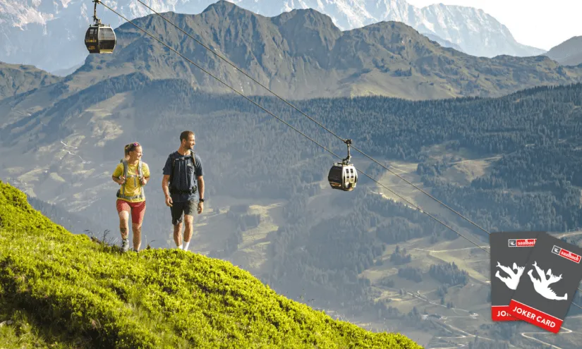 Wanderer mit Seilbahn und Joker Card im Hintergrund