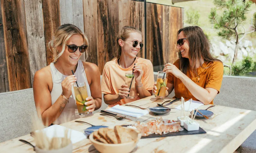 Drei Frauen genießen Getränke am Tisch in Saalbach Hinterglemm