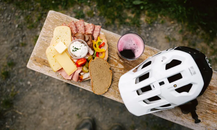 Holzbrett mit Wurst, Käse, Gemüse und einem Helm